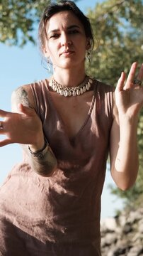 A beautiful brunette dressed in boho style meditates and dances in the forest. A magical ritual takes place against a green forest backdrop.