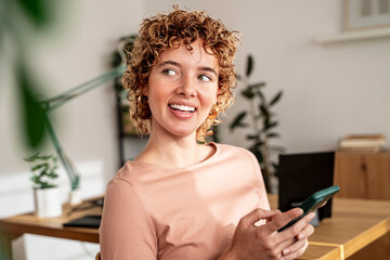 Smiling woman using smartphone in bright, peaceful organized office