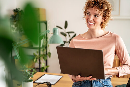 Smiling woman with laptop in bright modern organized home office