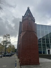 Obraz premium Berlin Germany October 2025 Gothic red brick remnant beside modern glass building under gray sky