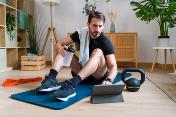 Man using training app for home fitness exercise with hydration