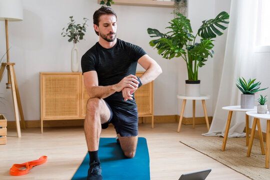 Athlete training at home with smartwatch in modern living room