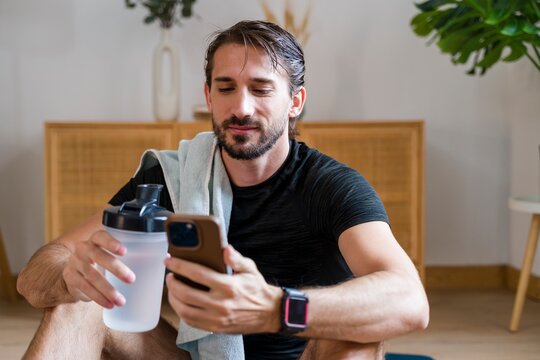 Man relaxing after home workout with towel and water bottle indoors