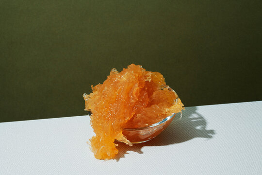 Bowl of shiny thick pumpkin jam on white tabletop with olive green wall