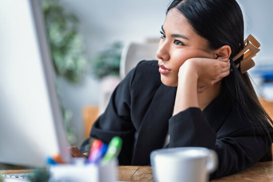Entrepreneur woman looking bored at her office desk with a computer and coffee cup