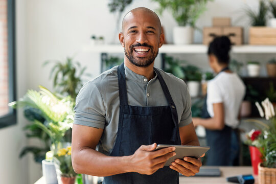 Entrepreneur smiling in plant store with tablet in apron