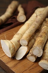 Fresh raw horseradish roots on wooden table, closeup