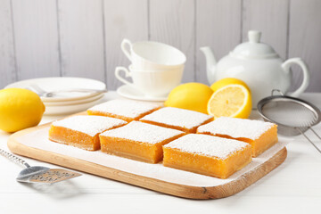 Tasty lemon bars, fresh fruits, server and sieve on white wooden table, closeup