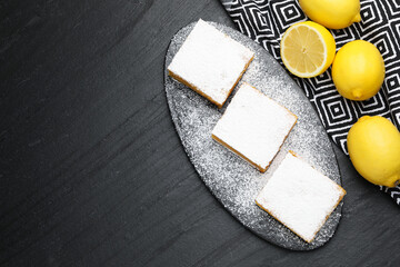 Tasty lemon bars and fresh fruits on black table, flat lay. Space for text