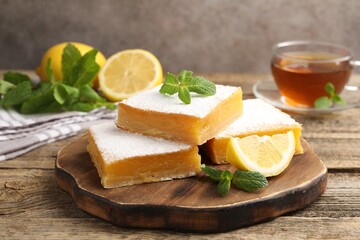 Tasty lemon bars with mint, fresh fruits and tea on wooden table, closeup
