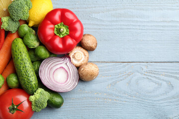 Different fresh raw vegetables and lemons on grey wooden table, flat lay. Space for text