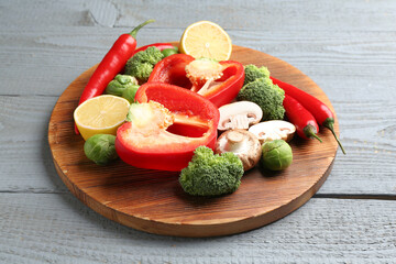 Different fresh raw vegetables and lemon on grey wooden table, closeup