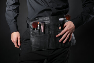 Makeup artist with set of brushes on black background, closeup