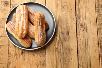 Delicious eclairs on wooden table, top view. Space for text