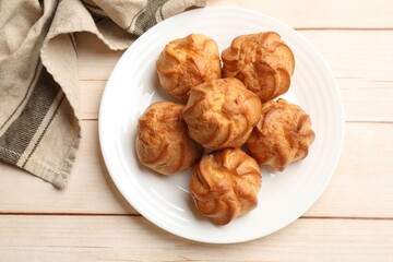 Delicious profiteroles and towel on white wooden table, top view