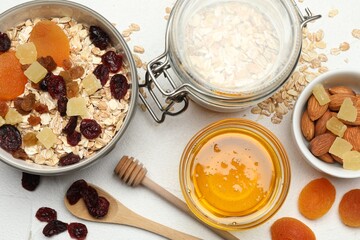 Making granola. Oat flakes, dried fruits and other ingredients on white table, flat lay