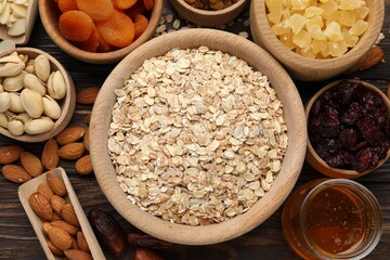 Making granola. Oat flakes, dried fruits and other ingredients on wooden table, flat lay