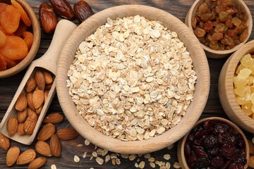 Making granola. Oat flakes, dried fruits and other ingredients on wooden table, flat lay