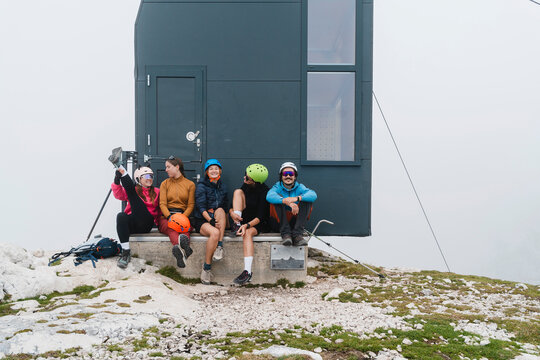 Group resting after trekking outside mountain hut with climbing gear