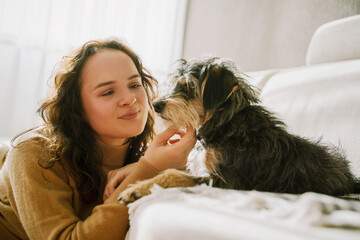 Woman cuddling dog on sofa and relaxing at home in serene moment