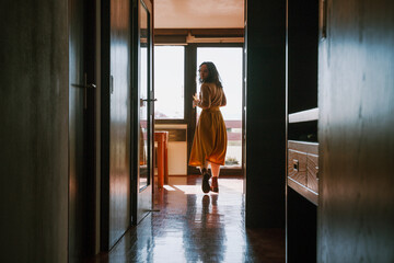 Woman walking in morning sunlight at home in serene minimalist interior