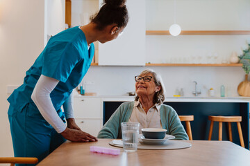 Nurse providing care and companionship during a meal at home