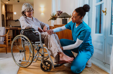 Caregiver assisting senior in wheelchair with rehabilitation exercises indoors