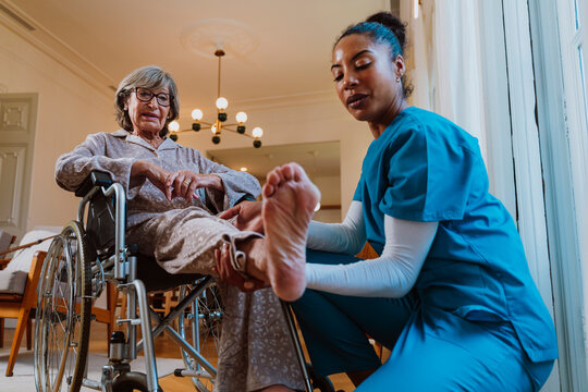 Caregiver helping senior in wheelchair with physical rehabilitation exercises