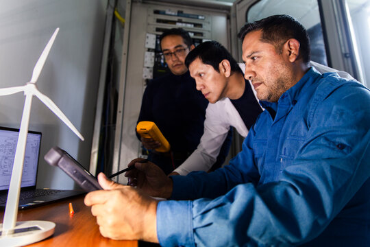 Engineers and inspector analyzing data in a control room with a focus on renewable energy technology