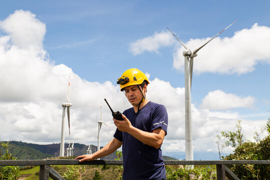 Engineer inspecting wind turbines at a wind farm using a walkie-talkie