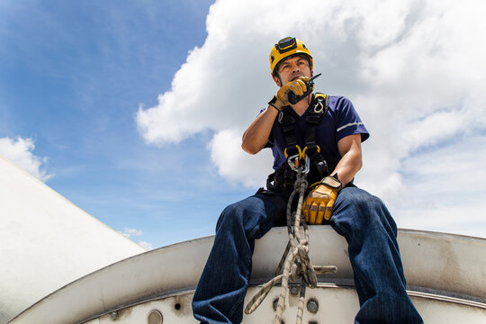 Engineer performing maintenance on top of a wind turbine nacelle outdoors