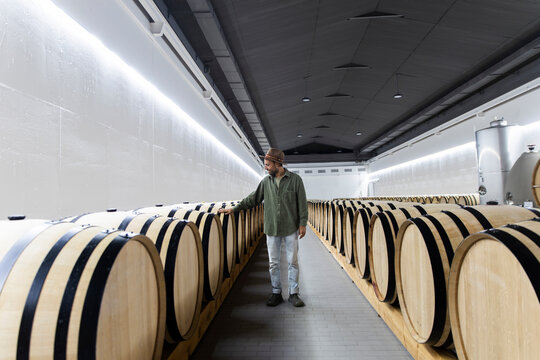 Person inspecting wine barrels in a modern winery cellar in Spain