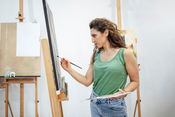 Artist painting at an easel in art studio with focus and creativity