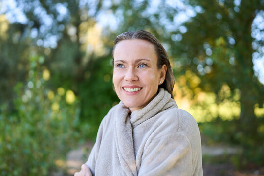 Smiling woman in bathrobe enjoying nature outdoors