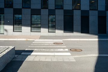 Architecture facade with windows arranged in geometry under sunlight and shadow, producing minimalism, structure, pattern and contrast across the clean modern exterior