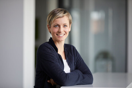 Businesswoman smiling in modern office with crossed arms