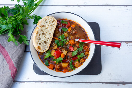Goulash soup with meat paprika carrot parsley and baguette overhead