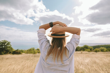 Woman stands in field with hat enjoying peaceful solitude outdoors