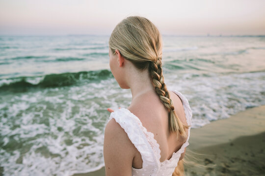 Rear view of person with braid watching waves in peaceful beach moment