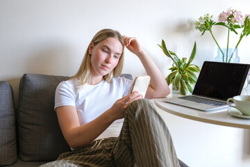 Woman working remotely on laptop and phone in cozy home environment