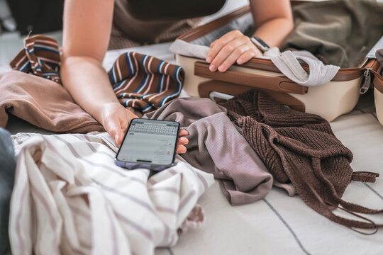 Person organizing capsule wardrobe and packing suitcase for travel