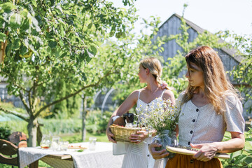 Women arranging outdoor breakfast table in summer garden