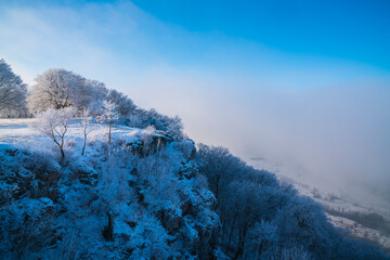 Germany, White snow covered rocks and cliffs on breitenstein mountain swabian alb national park nature landscape with fog in winter early morning blue sky panorama view