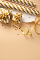 Christmas gift wrapping with golden and white striped wrapping paper, ribbon, scissors, and small gift boxes on beige backdrop. Copy space.