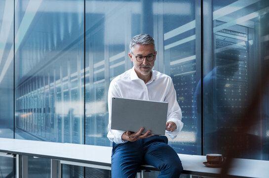 Engineer using laptop for data analysis in modern server room