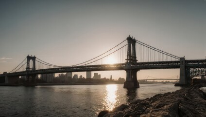 Obraz premium A suspension bridge arches over water, silhouetted against the setting sun, a distant city skyline visible