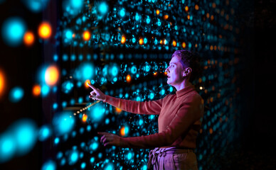 Engineer analyzing data on illuminated interface in server room