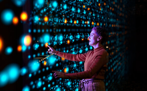 Engineer analyzing data on illuminated interface in server room