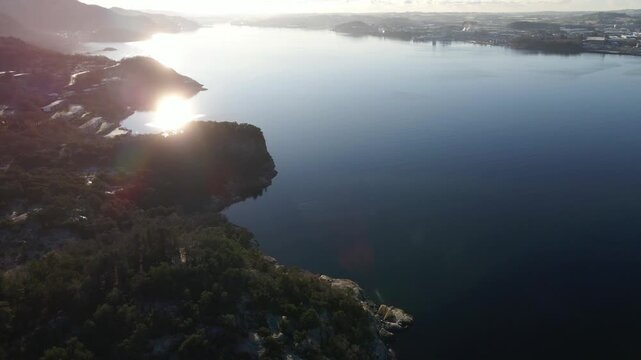 Aerial drone footage showing coastal mountains along the ocean on a winter day. The landscape features snow-covered terrain, cold light, and calm coastal water, creating a clear and atmospheric Nordic
