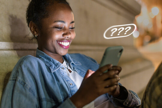 Smiling woman chatting with AI chatbot on mobile phone at night